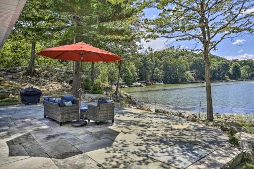 a patio with two chairs and an umbrella next to a river at Serene Hopatcong Cottage with 50-Foot Dock! in Hopatcong