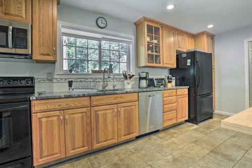 a kitchen with wooden cabinets and a black refrigerator at Serene Hopatcong Cottage with 50-Foot Dock! in Hopatcong