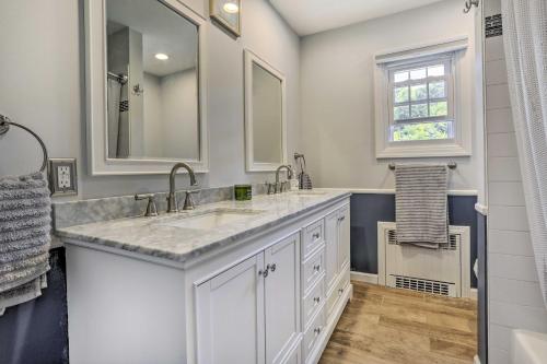 a white bathroom with two sinks and a window at Serene Hopatcong Cottage with 50-Foot Dock! in Hopatcong
