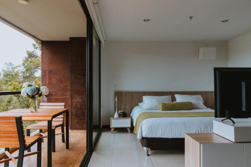 Travelers Rio Verde Living Suites في ريونيغرو: غرفة نوم بسرير وطاولة وتلفزيون