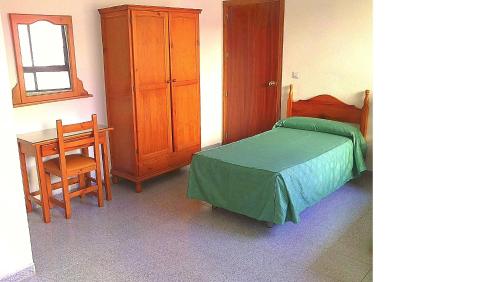 a bedroom with a bed and a table and a cabinet at Hostal Centro Ejido in El Ejido