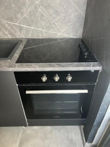 a black stove in a kitchen with a sink at Capsule Art Déco - Jacuzzi - Netflix - Home Cinéma - Arcade de jeux & Nintendo switch - 2 chambres - Filet suspendu in Valenciennes
