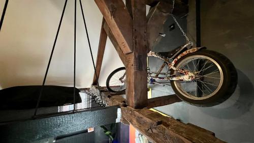 a bicycle is hanging from a wooden wall at Capsule Art Déco - Jacuzzi - Netflix - Home Cinéma - Arcade de jeux & Nintendo switch - 2 chambres - Filet suspendu in Valenciennes