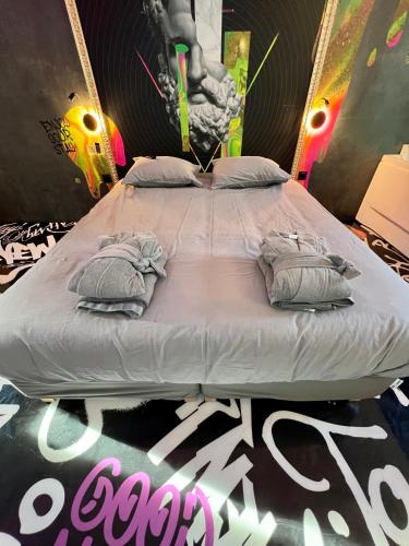 a large bed in a room with a poster on it at Capsule Art Déco - Jacuzzi - Netflix - Home Cinéma - Arcade de jeux & Nintendo switch - 2 chambres - Filet suspendu in Valenciennes