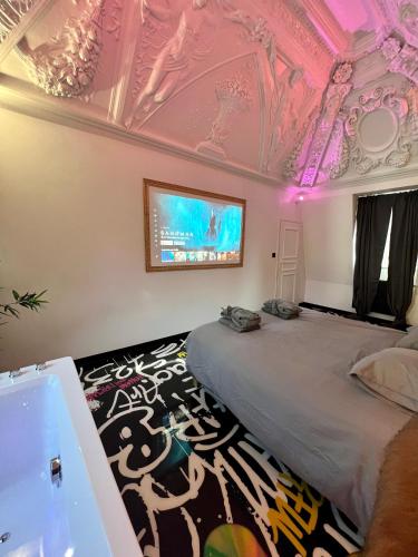 a bedroom with a bed and a tv on the ceiling at Capsule Art Déco - Jacuzzi - Netflix - Home Cinéma - Arcade de jeux & Nintendo switch - 2 chambres - Filet suspendu in Valenciennes