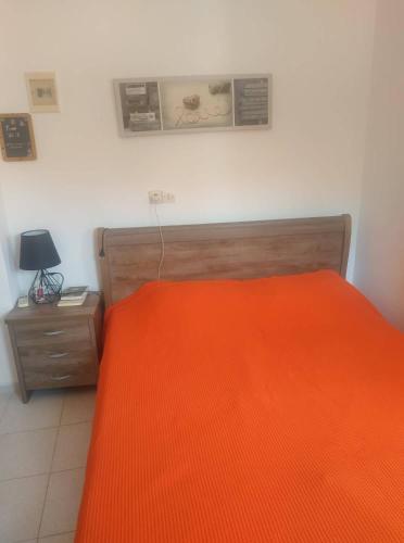 a bedroom with an orange bed and a night stand at Spiros Apartments in Livadia