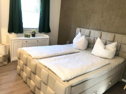 a large bed with white pillows on top of it at *Premium-Apartment im Spreewald* in Burg
