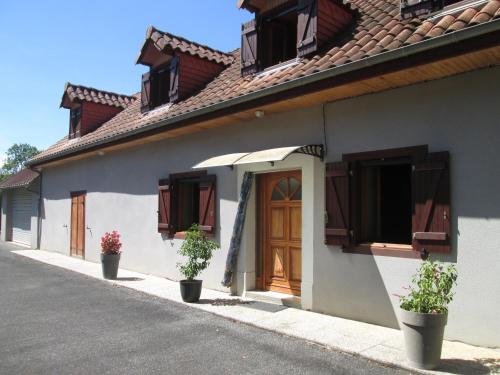 a white building with wooden doors and potted plants at Gîte de benque in Benqué