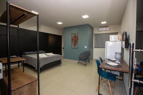 a room with a bed and a table and a refrigerator at Jahu Center Plaza Flats in Jaú