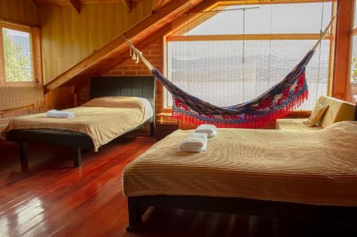 a room with two beds and a hammock in it at Cabaña en La Cocha - Janaxpacha in Los Alisales
