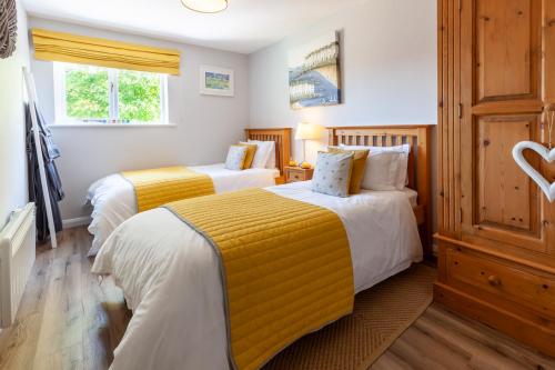 a bedroom with two beds with yellow and white sheets at St. Andrew's Prospect - Norfolk Cottage Agency in Norwich