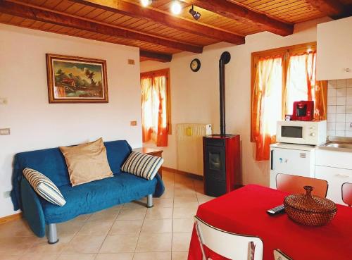 uma sala de estar com um sofá azul e uma cozinha em Alloggio Matrimoniale vicino Asiago (Roana) em Roana
