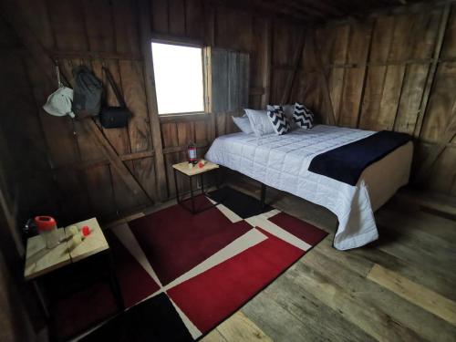 1 dormitorio con 1 cama en una cabaña de madera en BIRDGLAMPING LOS ÁRBOLES-Estación Biológica LA GUAYANA, en Salento