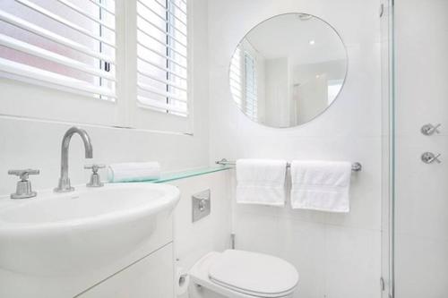 a white bathroom with a sink and a mirror at BADEN - Absolute Water Front Sydney Harbour Studio in Sydney