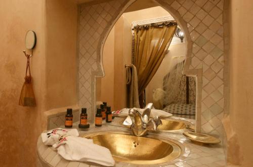 baño con lavabo de oro y espejo en Riad El Bellar, en Marrakech