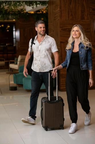 a man and a woman standing with a suitcase at Novotel Sao Paulo Morumbi in Sao Paulo