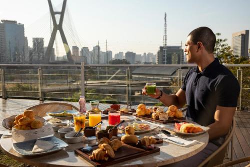 a man sitting at a table with a plate of food at Novotel Sao Paulo Morumbi in Sao Paulo