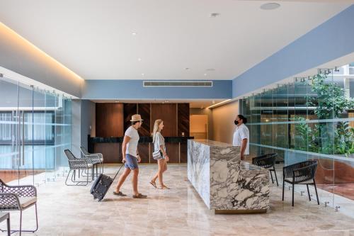 a group of people walking through an airport with luggage at Singular Dream Beach Residences in Playa del Carmen