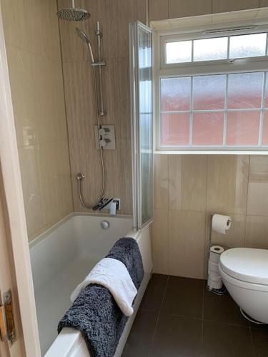 a bathroom with a tub and a toilet and a window at Lovekush Epsom Banstead Surrey. Views over London in Ewell