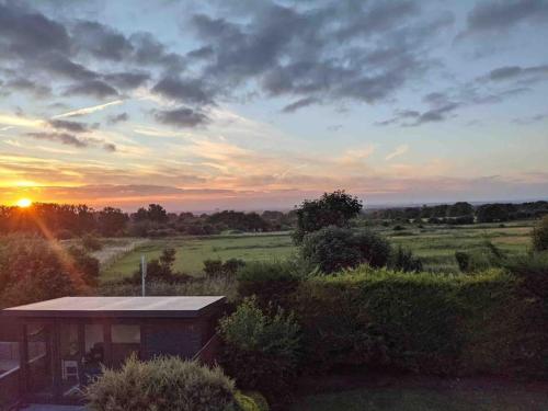 a house in a field with the sunset in the background at Lovekush Epsom Banstead Surrey. Views over London in Ewell