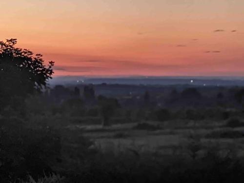 a sunset over a field with a city in the distance at Lovekush Epsom Banstead Surrey. Views over London in Ewell