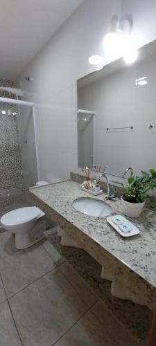 a bathroom with a sink and a toilet and a mirror at Pousada da Vila in Itaipava