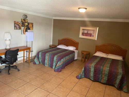 a hotel room with two beds and a desk at Budgetel Inn and Suites - Louisville in Louisville