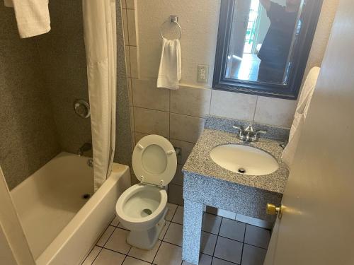 y baño con aseo, lavabo y bañera. en Budgetel Inn and Suites - Louisville en Louisville