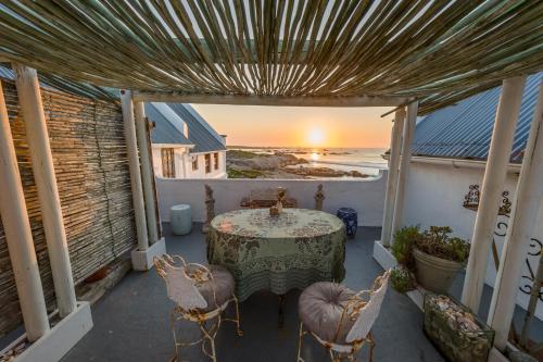 a table and chairs on a balcony with a view of the ocean at The Oystercatchers Haven at Paternoster in Paternoster