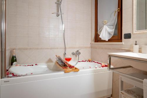 SUITE LEONARDO RELAX في فيوميتشينو: حمام مع حوض مع كوب من النبيذ