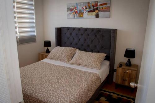 a bedroom with a bed and two night stands with lamps at Quedate aqui Centro Concepcion I in Concepción
