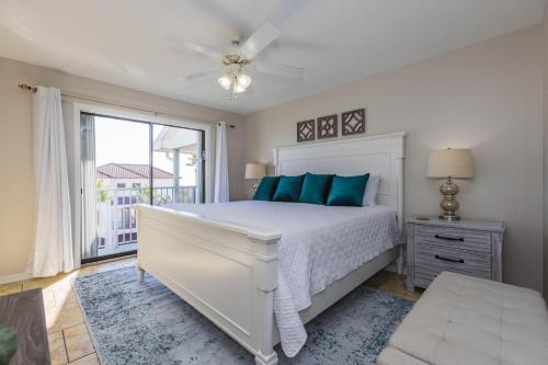 a white bedroom with a bed and a window at Sunshine At The Beach in Orange Beach