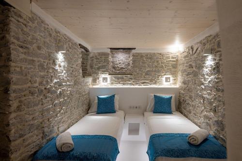 Habitación con 2 sofás contra una pared de piedra. en Margaret's Houses in TINOS Town en Tinos Town