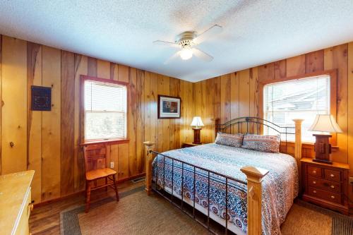 a bedroom with wooden walls and a bed and two windows at Pirate's Light #73-B in Buxton
