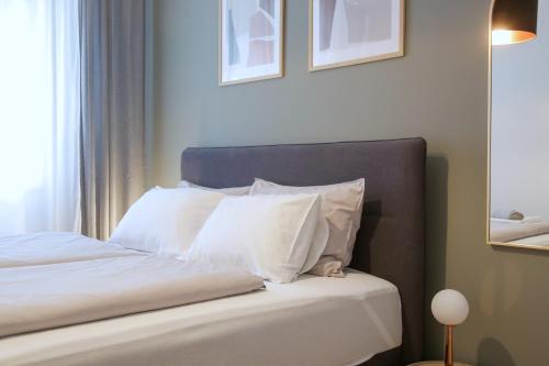 een slaapkamer met een bed met witte kussens bij Supernova City Center - FREE PRIVATE PARKING in Novi Sad