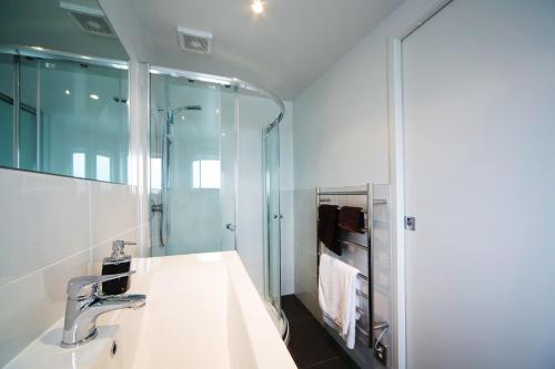 y baño con lavabo y espejo. en Kohi Beach Bed & Breakfast, en Auckland