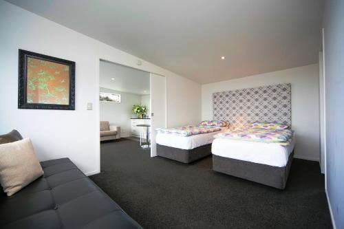 a hotel room with two beds and a couch at Kohi Beach Bed & Breakfast in Auckland