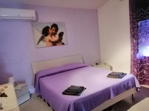 ein Schlafzimmer mit einem lila Bett und einem Bild einer Frau in der Unterkunft Villetta immersa nel verde in Piazza Armerina