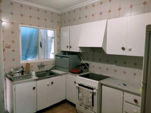 uma cozinha com armários brancos, um lavatório e uma janela em Apartamento Bellas Vistas. em El Verger