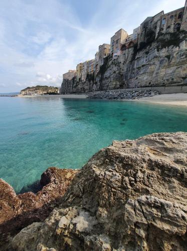 a beach with turquoise water and a rocky shore at Caia Appartamenti Tropea in Tropea