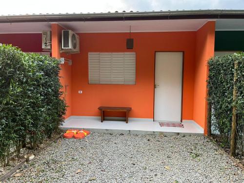an orange house with a bench in front of it at Chalés Caminhos do Cacau Camburi in Sao Paulo