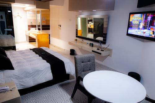 a bedroom with a bed and a tv and a table at Hotel Contadero Suites y Villas in Mexico City