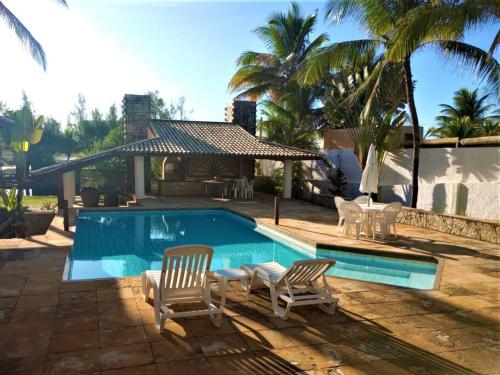 una piscina con due sedie e una casa di Casa em Interlagos a Camaçari