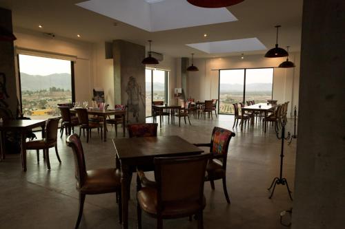 a dining room with tables and chairs and windows at Estancias Sierravita in Valle de Guadalupe