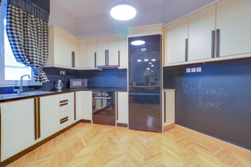 a kitchen with white cabinets and a wooden floor at AthINN Residence in Athens