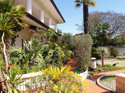 un jardin en face d'une maison avec des plantes et des arbres dans l'établissement Residenza ZACCOLO, à Lignano Sabbiadoro