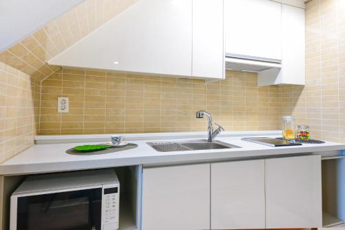 a kitchen with a sink and a microwave at Jeju Resort in Jeju