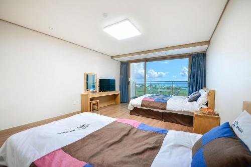 pokój hotelowy z 2 łóżkami i dużym oknem w obiekcie Jeju Resort w mieście Czedżu