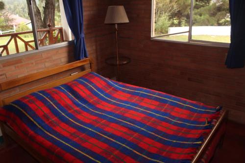 a bed with a red and blue striped blanket on it at Cucunuba por Siempre in El Salitre