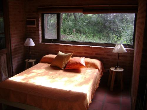 Un dormitorio con una cama con dos lámparas y una ventana. en Alpa'y Kanki, en Alpa Corral